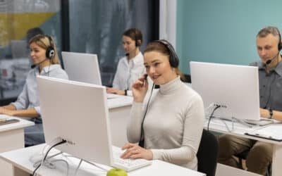 Equipe de atendimento em call center usando headsets e computadores em escritório moderno.