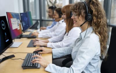 Equipe de call center usando headsets e computadores em linha; foco em atendente sorridente ao teclado.