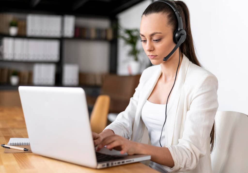 Atendente de call center utilizando headset enquanto realiza atendimento com serviço de callback em um notebook.