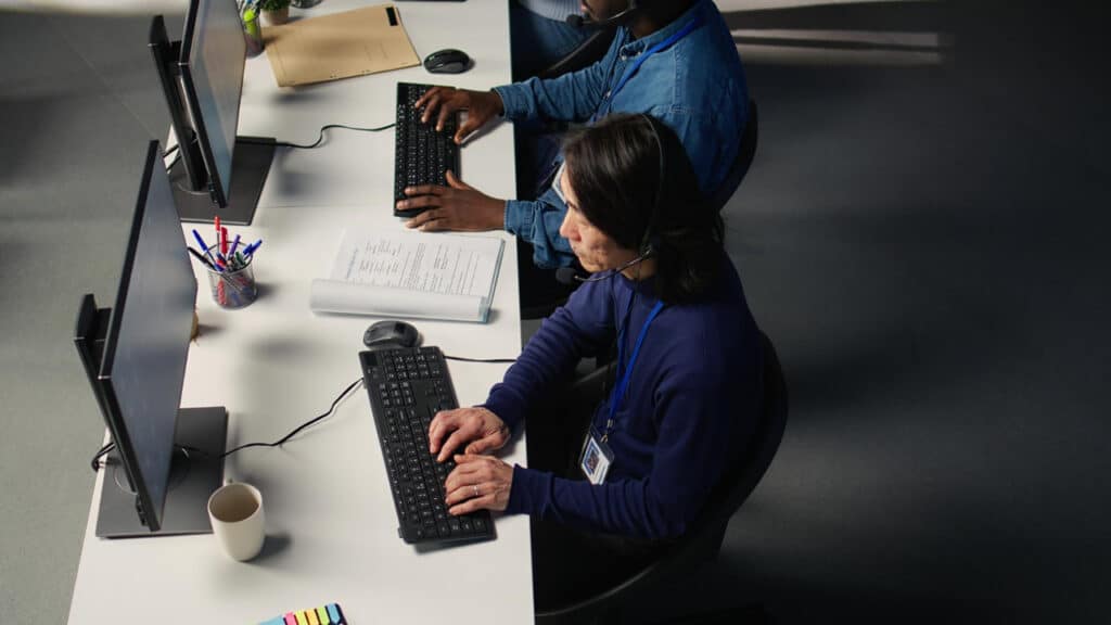 Profissionais realizando atendimento telefônico em operação de contact center com headsets e computadores.