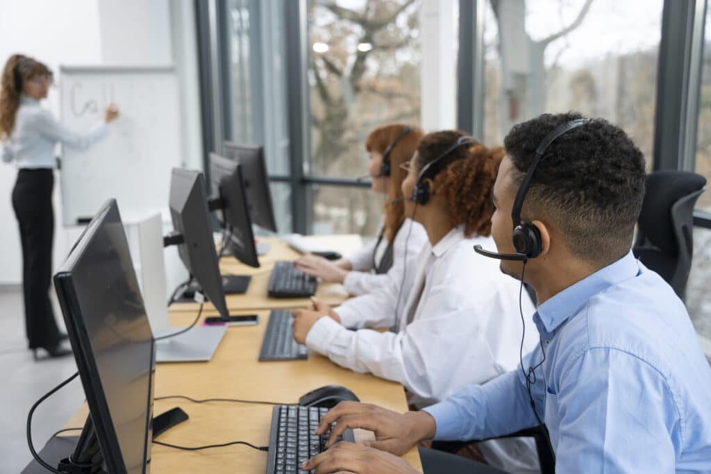 Equipe de atendimento trabalhando em um contact center com headsets e computadores.