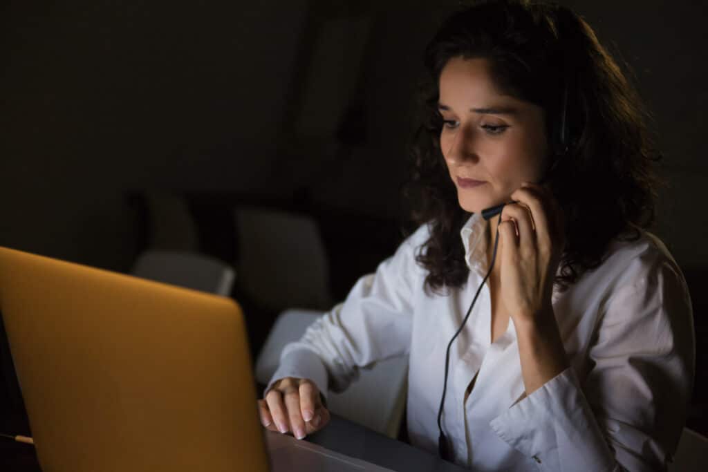 Profissional realizando uma operação de cold call com headset e notebook para prospecção ativa por telefone.